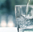 Close up pouring purified fresh drink water from the bottle on table in living room - Северный город